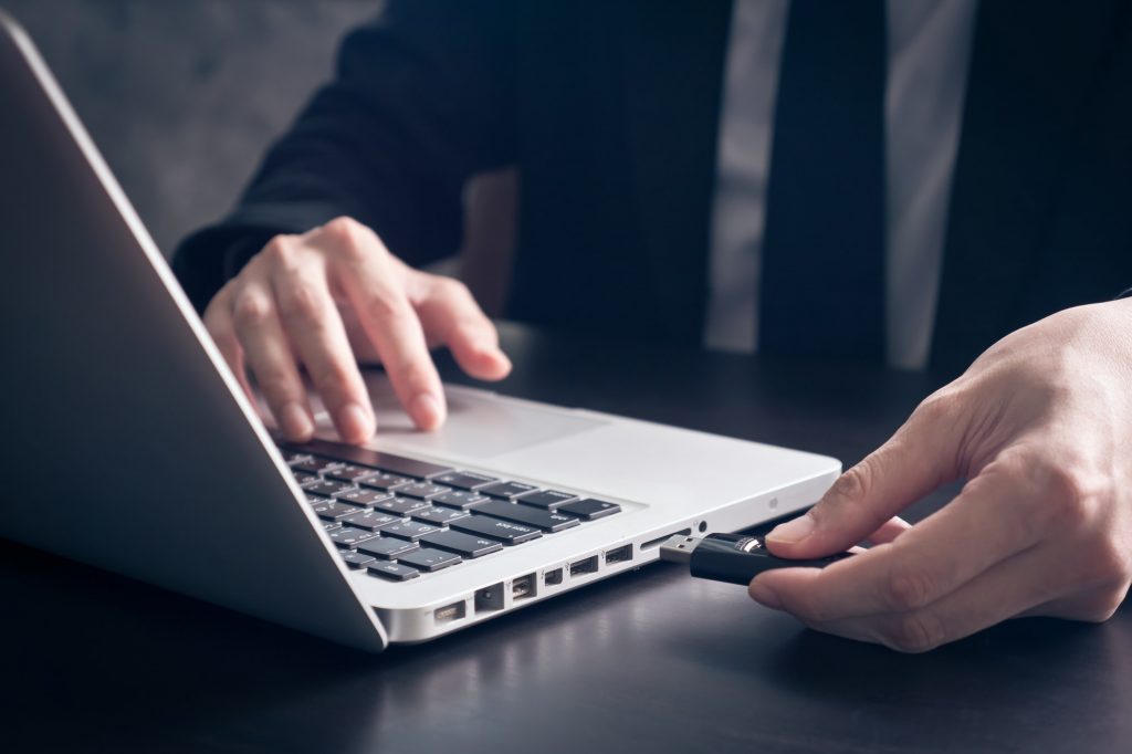 Close up of Businessman using flash drive connect to laptop on the office desk.