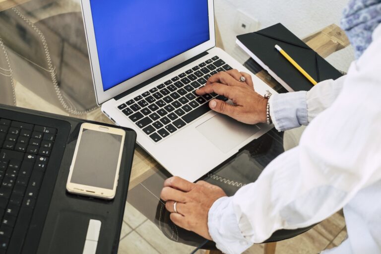 Close up and above view of woman hands typing on a keyboard and working with two laptop