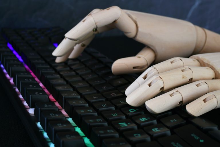 AI artificial intelligence concept - robot hands typing on lit keyboard