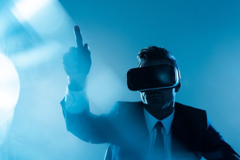 businessman in virtual reality headset pointing on something isolated on blue, artificial