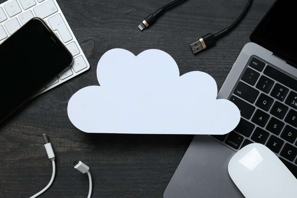 White, paper cloud with various gadgets on a black table background
