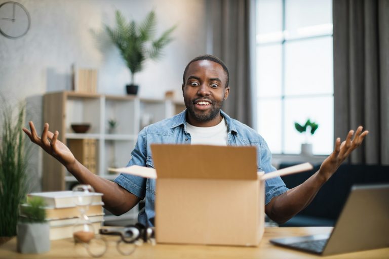 African man sitting at desk and doing unpacking of box